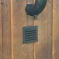 Load image into Gallery viewer, Ventilation system on a wooden wall with a black pipe and air inlet grate. 
