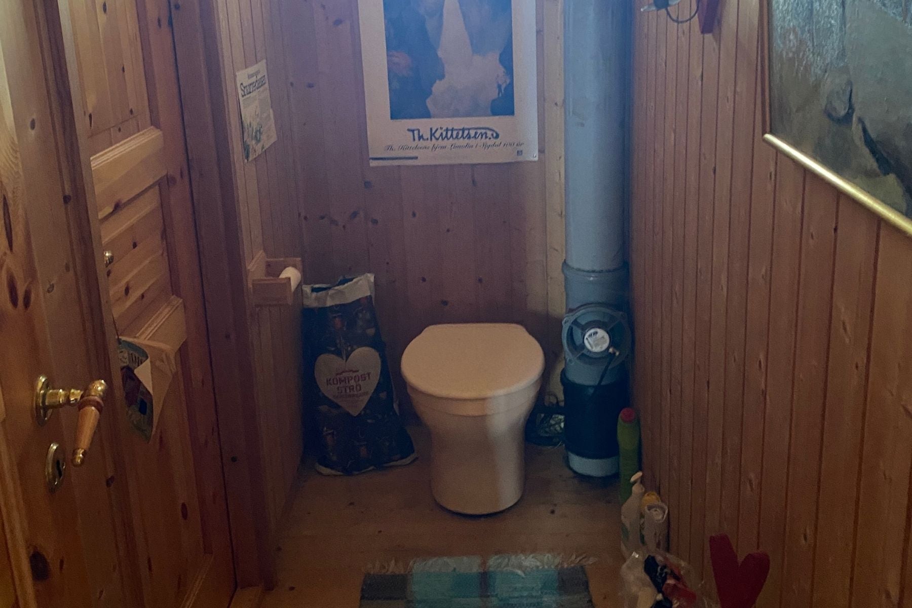 Bathroom with wooden walls and an unpleasant toilet solution.