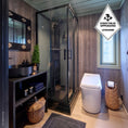 Load image into Gallery viewer, Modern bathroom with shower, Cinderella Comfort incineration toilet, and wooden walls.
