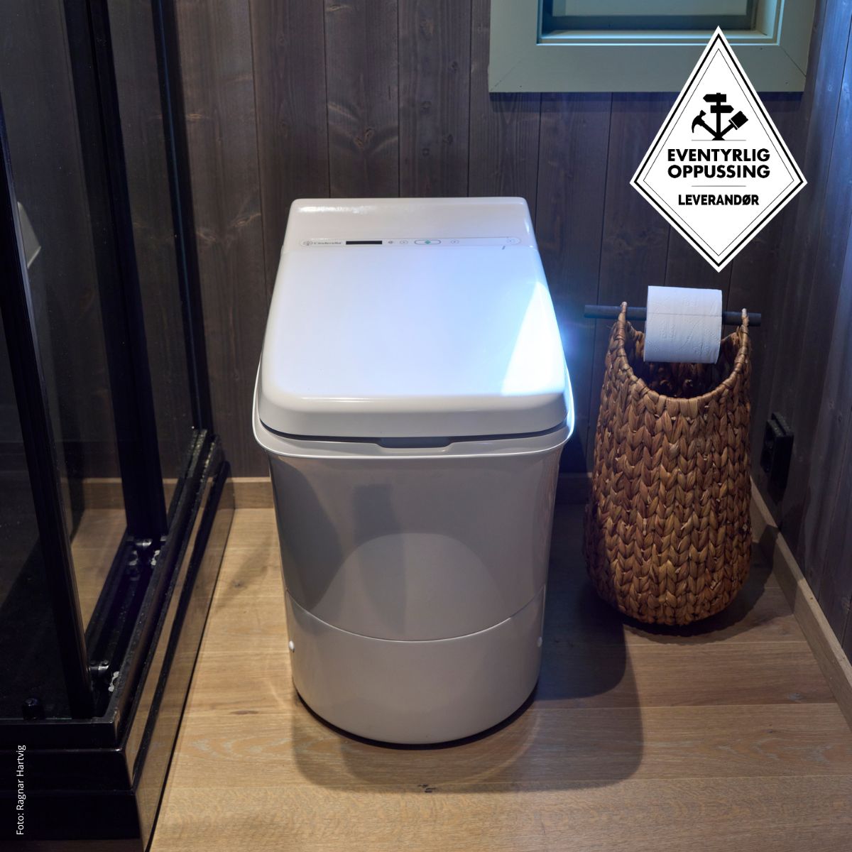 Cinderella Comfort incineration toilet in a bathroom with a woven basket and toilet paper roll.