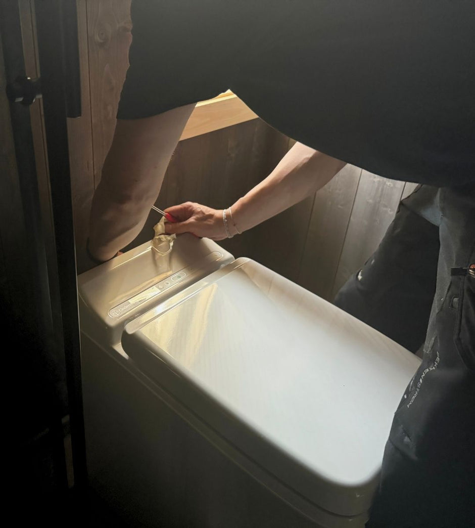 Person installing a Cinderella incineration toilet in a restroom.