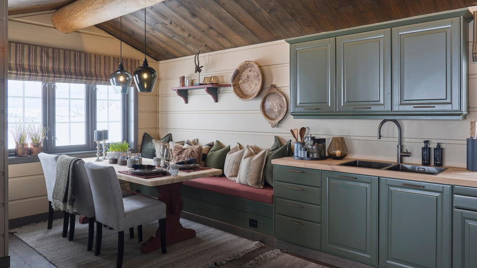 Kitchen with green cabinets, wooden dining table, and red cushioned bench.