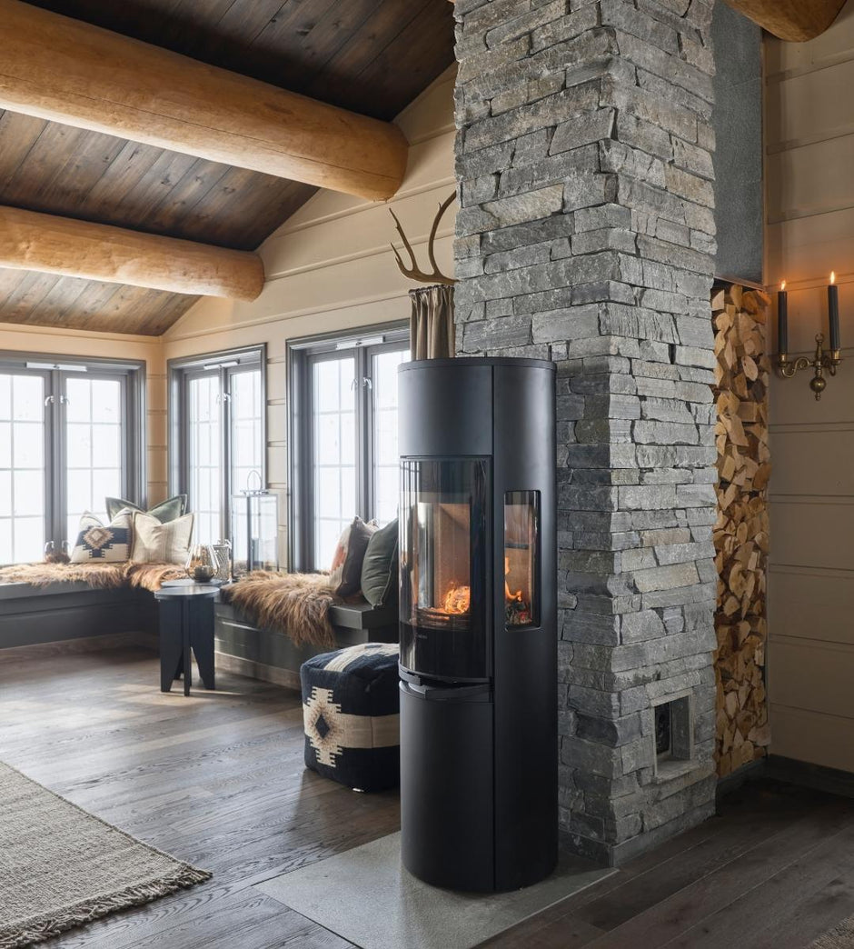 Modern stone fireplace in a cozy living room with wooden beams and large windows.
