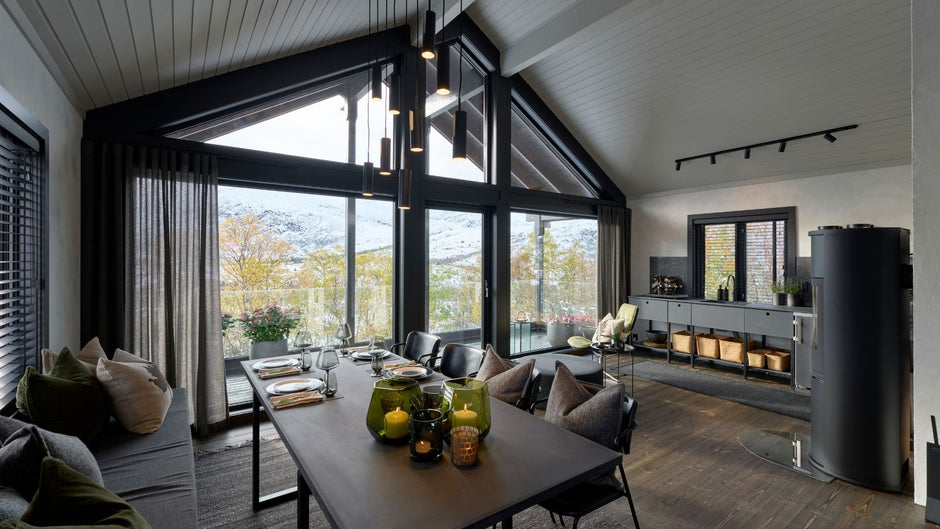 Modern living room with large windows, furniture, and decorative items.