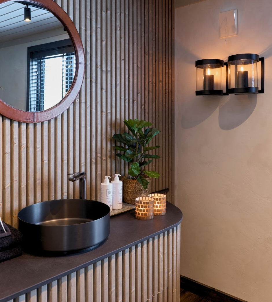 Bathroom with round mirror, black sink, and decorative elements.
