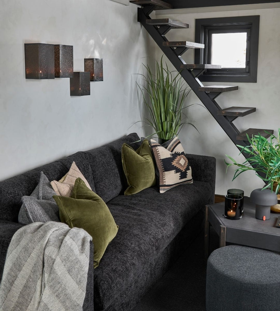Living room with a gray sectional sofa, decorative pillows, and a staircase in the background.
