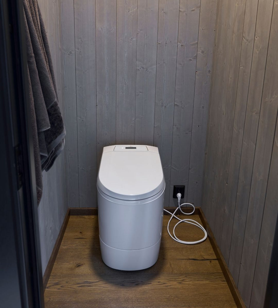 Cinderella Premium incineration toilet with electronic control panel in a bathroom with wooden floor and wall.