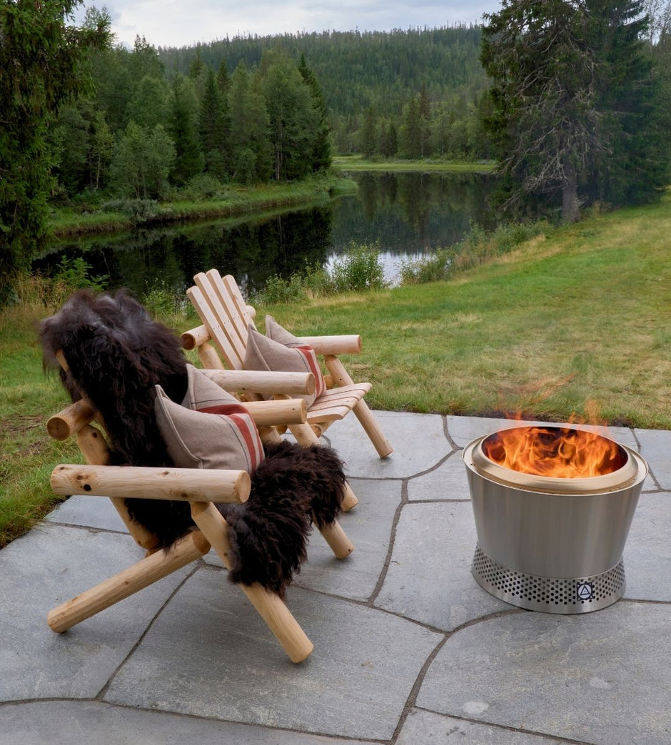 Kaksi puutuolia nuotiopaikan äärellä, josta avautuu kaunis näkymä järvelle ja metsään.