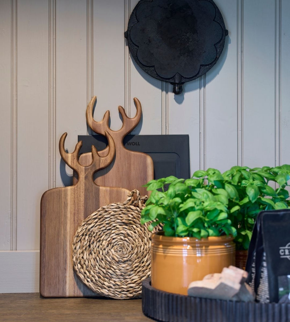 Koriste-esineitä, kuten puisia leikkuulautoja ja ruukkukasvi seinää vasten.