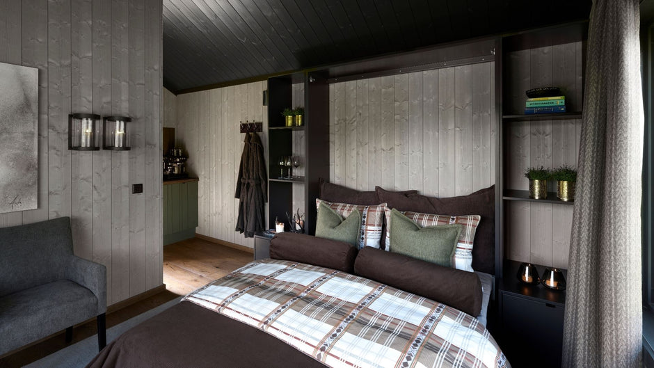 Modernt sovrum med en säng, hyllor och en grå soffa.